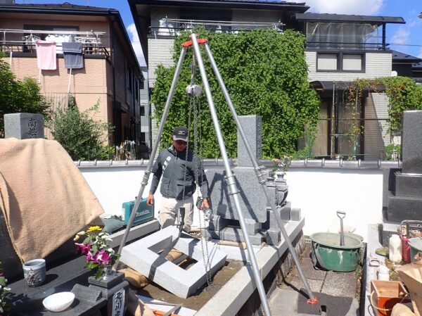 三ツ又クレーンで一枚石の御影石納骨室を設置する作業